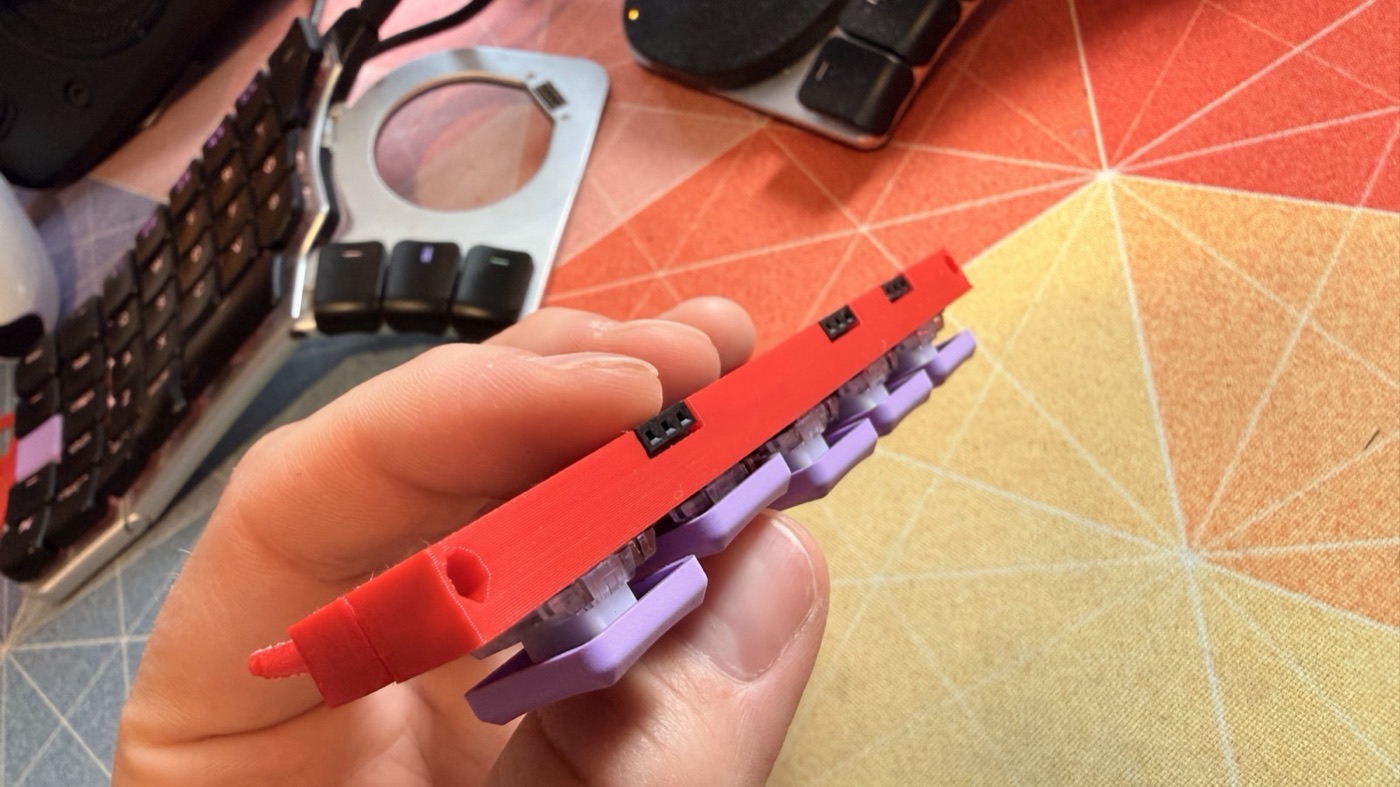 A finished key module held in a hand, with connector openings along its side