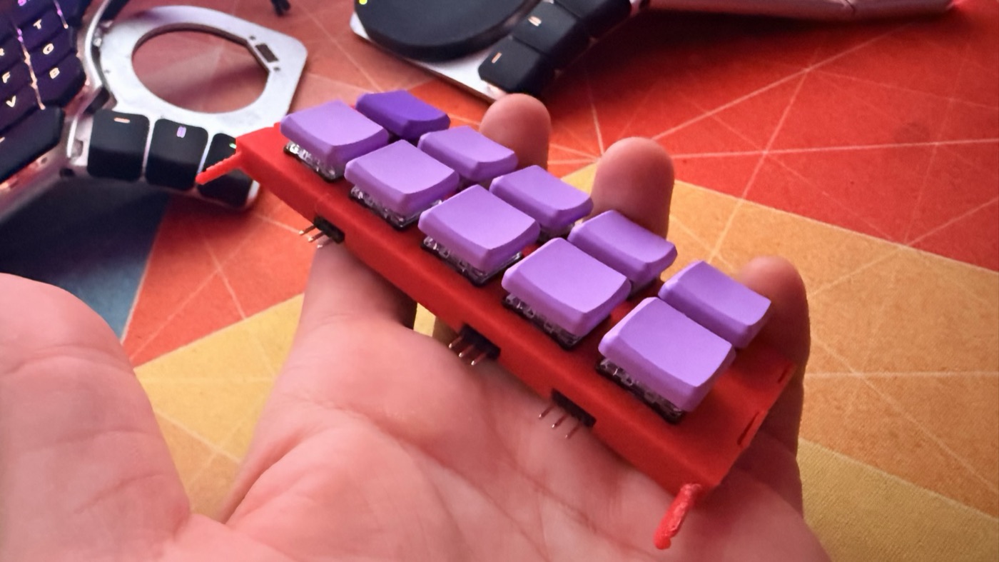 Two joined key modules with purple keycaps held in a hand